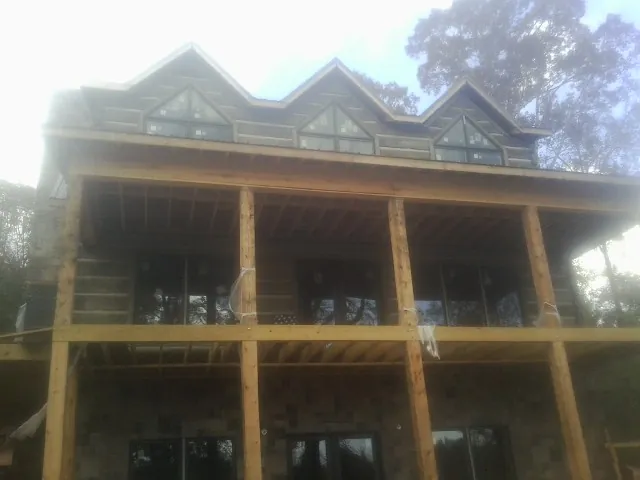 Dormers and porch framing on a large log home under construction — Roof Coating work by our crew in Topeka