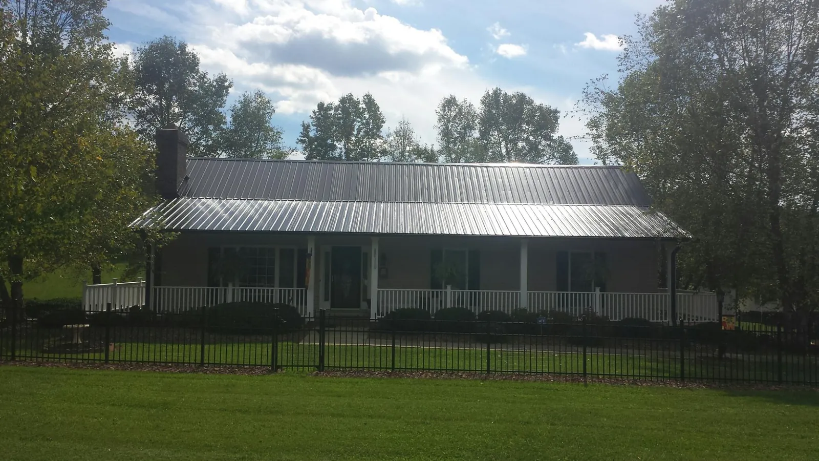Gray metal roof on a brick ranch with a full width front porch — Gutter Guard Installation work by our crew in Topeka