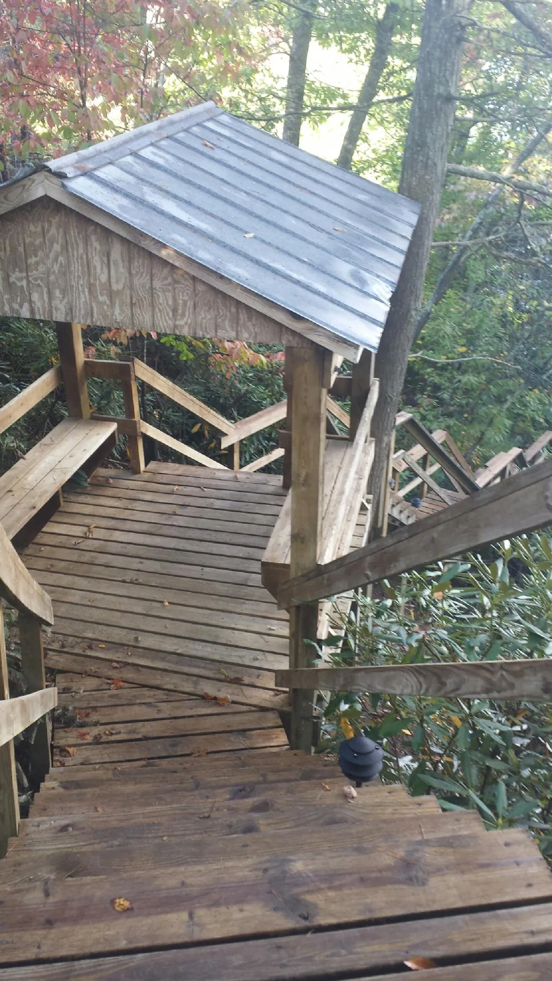 Metal roofed shelter over wooden steps on a wooded walkway — Skylight Repair & Installation work by our crew in Topeka