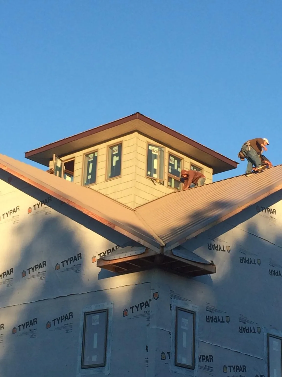 Roofers working around a rooftop cupola on a new metal roof at sunset — Roof Waterproofing in Topeka by Roofing Brothers